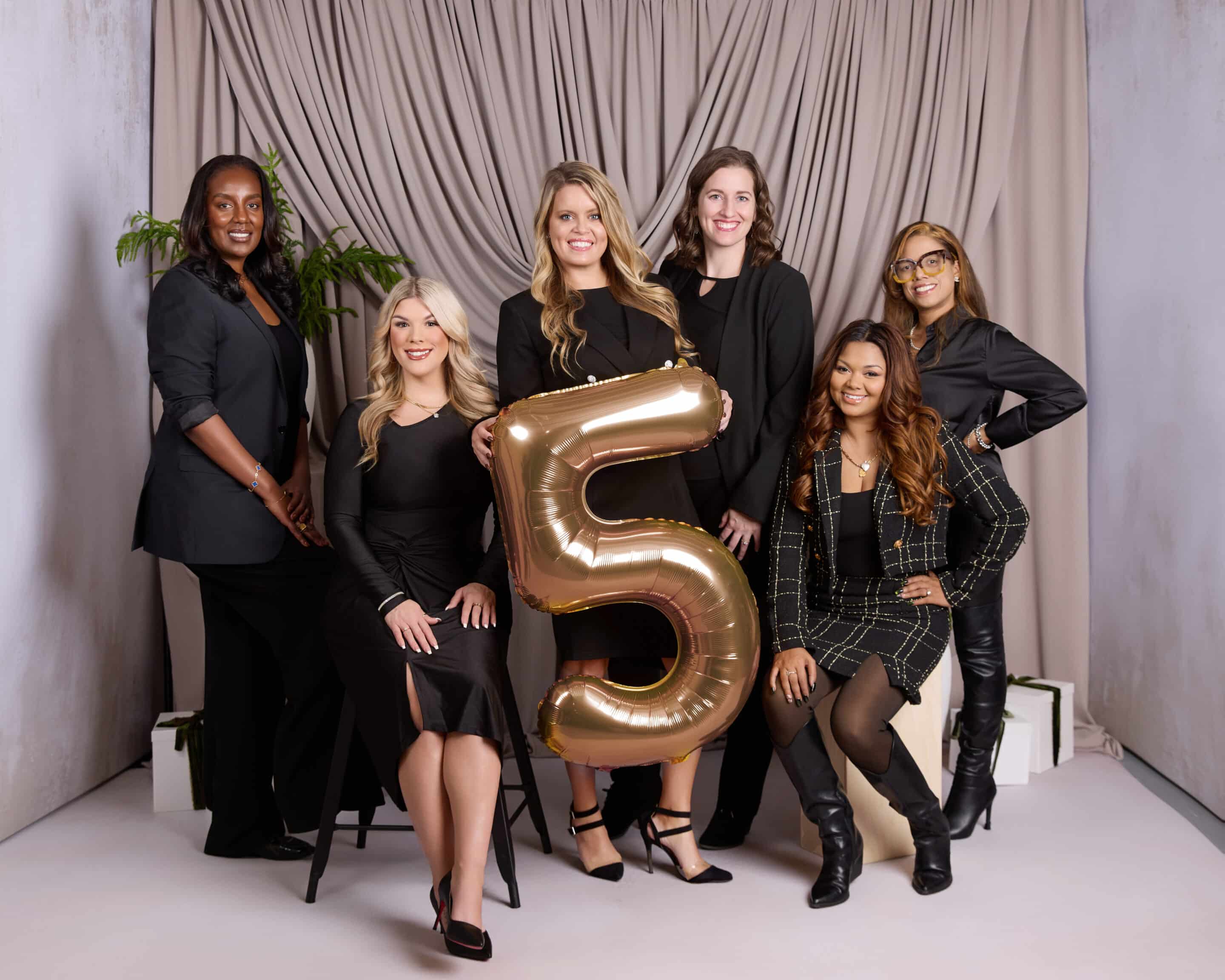 Rise Real Estate agents holding up a golden "5" balloon in a group photo
